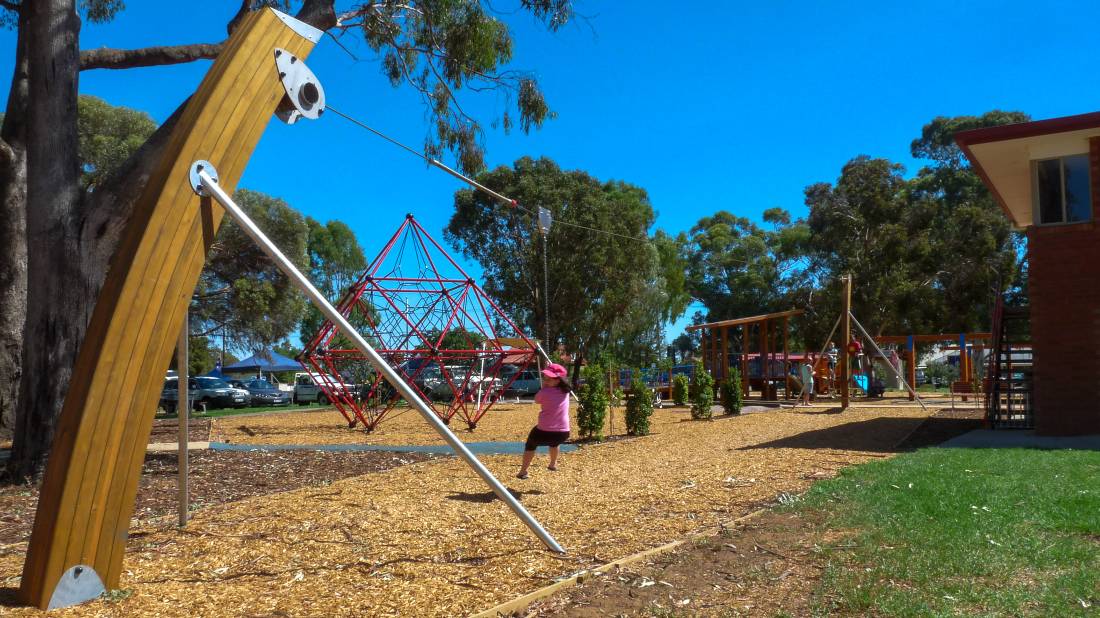 Playground with climbing structures, slide and swing in spacious park.