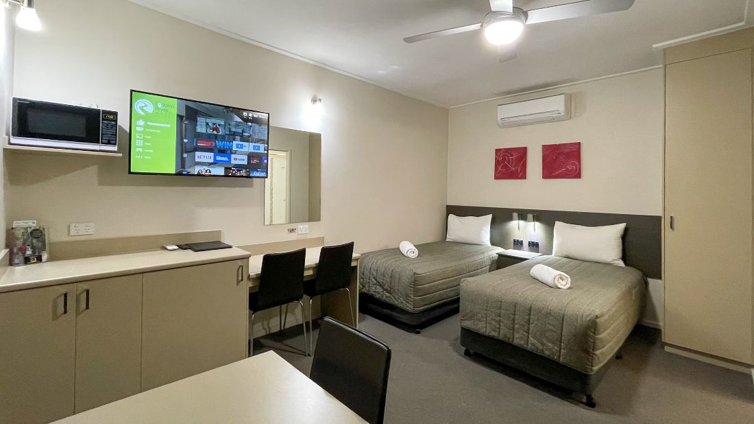 Modern motel room with two single beds, kitchenette and dining area