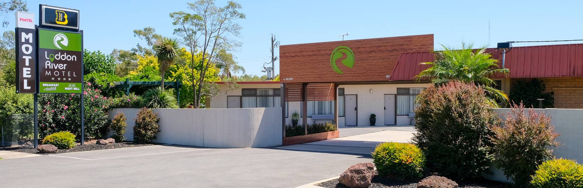 Loddon River Motel frontage with red roof, white wall units, signage and gardens