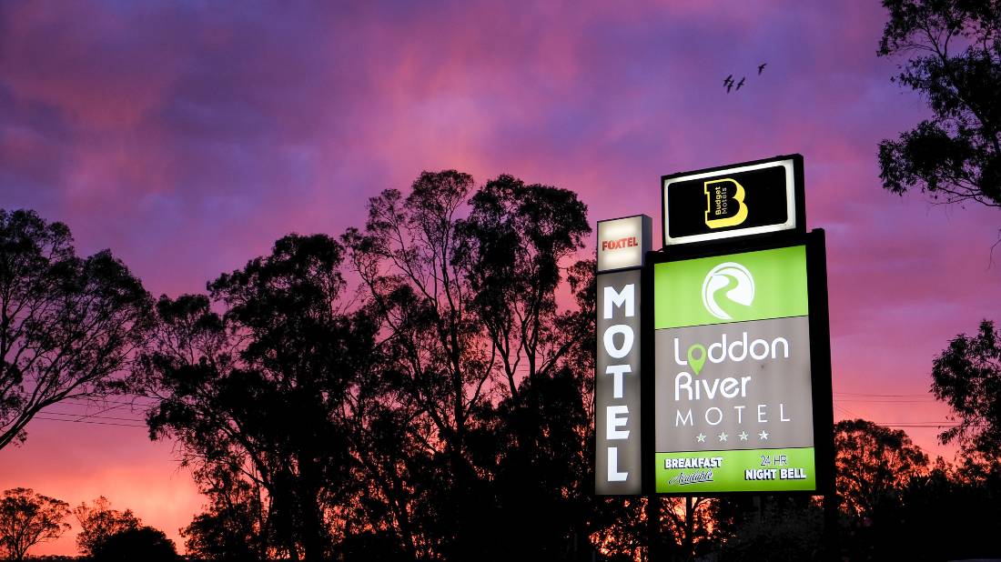 Motel signage against purple sunset sky with silhouetted eucalyptus trees