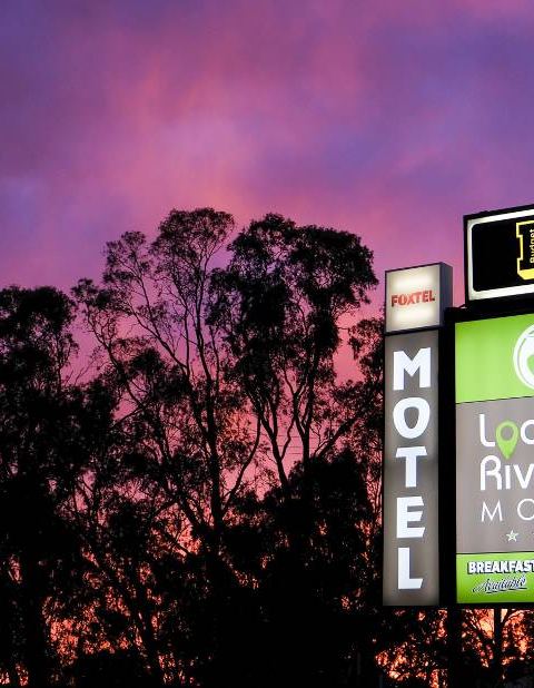 Motel signage against purple sunset sky with silhouetted eucalyptus trees